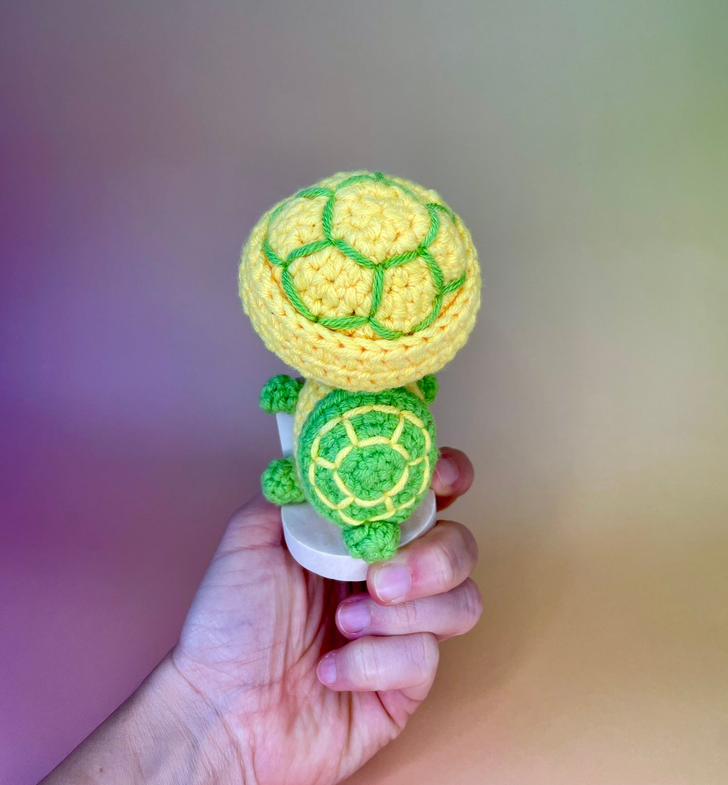 Premium positive Schildkröte - gehäkelte Figur mit motivierender Botschaft in der Hand gehalten von hinten gezeigt